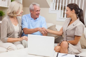 Saleswoman Shaking Hands With Senior Couple at Home